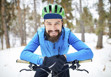 Porträt eines glücklichen Mannes mit Fahrrad auf einem schneebedeckten Berg - CAVF58730