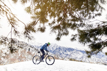 Seitenansicht eines Mannes beim Fahrradfahren auf einem schneebedeckten Berg gegen den Himmel - CAVF58732
