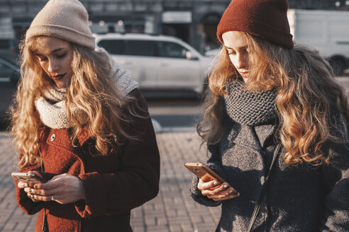 Schwestern benutzen Mobiltelefone, während sie auf der Straße stehen - CAVF58772