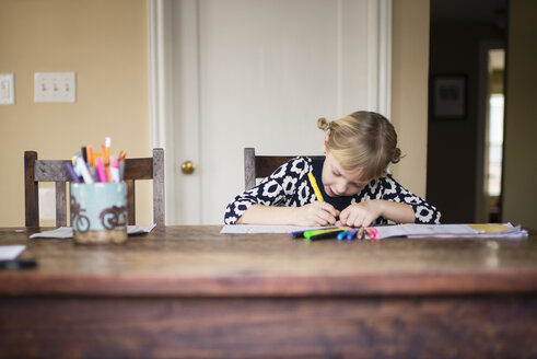 Mädchen macht Hausaufgaben, während sie zu Hause sitzt - CAVF58781