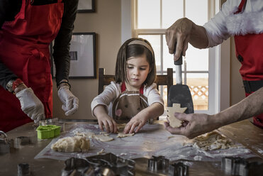 Enkelin hilft den Großeltern beim Backen von Weihnachtsplätzchen auf dem Tisch zu Hause - CAVF58829