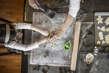 Draufsicht auf Enkelin und Großmutter beim Backen von Weihnachtsplätzchen auf dem Tisch zu Hause - CAVF58830