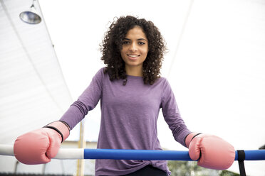 Portrait of smiling female boxer standing in boxing ring - CAVF58844