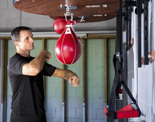 Boxtrainer beim Boxen mit dem Sandsack im Fitnessstudio - CAVF58845