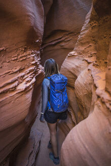 Rear view of female hiker with backpack walking amidst canyons - CAVF58870
