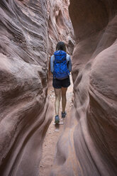 Rear view of carefree female hiker with backpack walking amidst canyons - CAVF58871