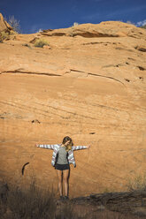 Full length of woman with arms outstretched standing against rock formations - CAVF58873
