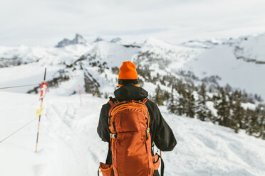 Rückansicht eines Wanderers mit Rucksack auf einem schneebedeckten Berg im Skiurlaub - CAVF58877