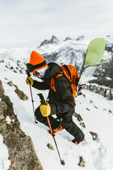 Hiker with backpack and ski poles climbing snowcapped mountain - CAVF58879