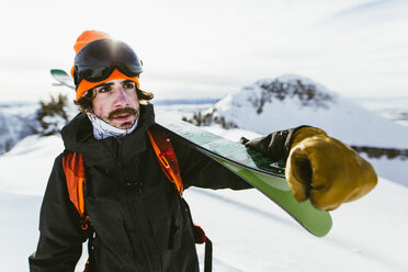 Wanderer mit Ski auf der Schulter vor einem schneebedeckten Berg - CAVF58881