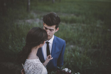 High angle view of bride with groom standing on grassy field in forest - CAVF58931