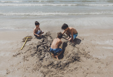 High angle view of shirtless brothers playing on shore at beach - CAVF58959