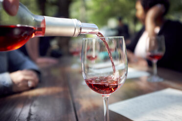 Rotwein in Weinglas auf Holztisch einschenken - CAVF58969