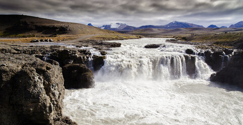 Landschaftlicher Blick auf einen Wasserfall bei bewölktem Himmel in Island - CAVF58972