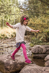 Seitenansicht eines Mädchens, das auf Felsen im Wald läuft - CAVF58981