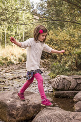 Side view of girl walking on rocks in forest - CAVF58981