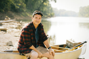 Porträt eines mittleren Erwachsenen, der auf einem Boot am Seeufer sitzt - CAVF59003