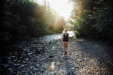Rückansicht eines unbekümmerten Mädchens, das im Wald auf einen Fluss zugeht - CAVF59108