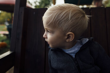 Close-up of boy looking away while sitting on outdoor play equipment - CAVF59124