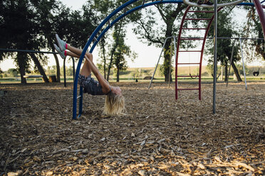 Seitenansicht eines glücklichen Mädchens, das auf einem Spielplatz auf einem Affengitter spielt - CAVF59137