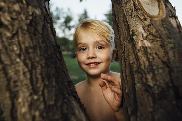 Portrait of boy standing by tree trunks - CAVF59158