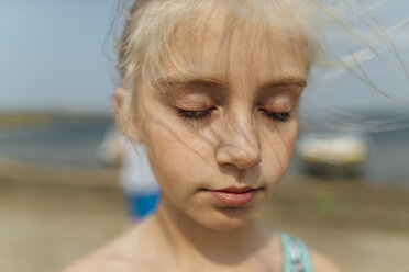 Nahaufnahme eines am Strand stehenden Mädchens mit geschlossenen Augen - CAVF59160