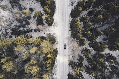 Blick von oben auf ein Auto auf der Straße inmitten von Nadelbäumen im Wald im Winter - CAVF59173