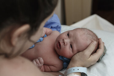 Shirtless newborn son looking at mother in hospital - CAVF59183