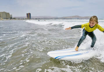 Chile, Arica, glücklicher Junge beim Surfen im Meer - SSCF00076