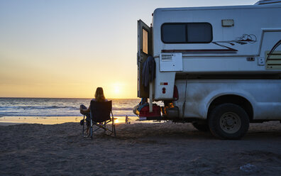 Chile, Arica, Frau sitzt neben Wohnmobil am Strand bei Sonnenuntergang - SSCF00079