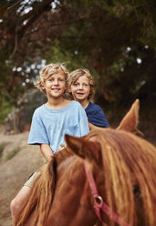 Porträt von zwei glücklichen Jungen auf einem Pferd in einem Wald - SSCF00092