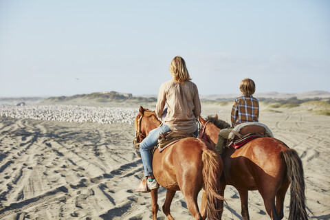 Chile, Vina del Mar, Mutter mit Sohn reitet auf Pferden am Strand, lizenzfreies Stockfoto