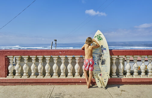 Chile, Pichilemu, Junge an Uferpromenade mit Surfbrett stehend - SSCF00116