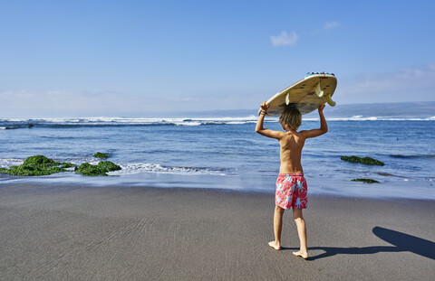 Chile, Pichilemu, Junge mit Surfbrett am Meer, lizenzfreies Stockfoto