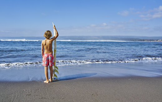Chile, Pichilemu, Junge am Meer stehend mit Surfbrett - SSCF00119