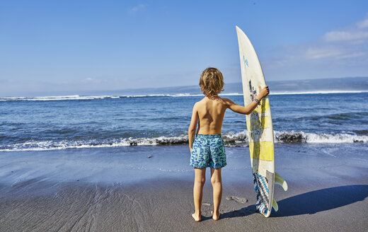 Chile, Pichilemu, Junge am Meer stehend mit Surfbrett - SSCF00121