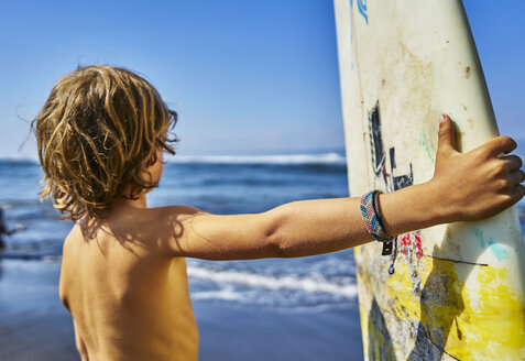 Chile, Pichilemu, Junge am Meer stehend mit Surfbrett - SSCF00122