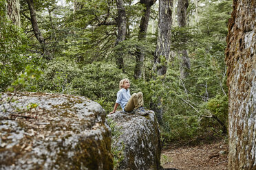Chile, Puren, Nahuelbuta National Park, Junge sitzt auf einem Felsen im Wald - SSCF00144