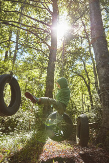 Junge balanciert auf Reifen in einem Abenteuerpark im Wald - SSCF00154