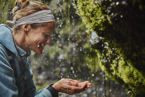 Chile, Patagonien, Vulkan Osorno, Frau erfrischt sich mit Wasser aus dem Wasserfall Las Cascadas - SSCF00175