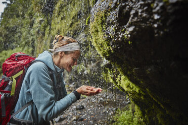 Chile, Patagonia, Osorno Volcano, woman refreshing with water from Las Cascadas waterfall - SSCF00176