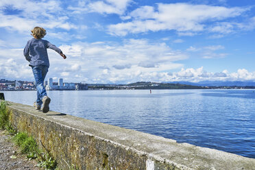 Chile, Puerto Montt, boy running on quay wall at the harbor - SSCF00183