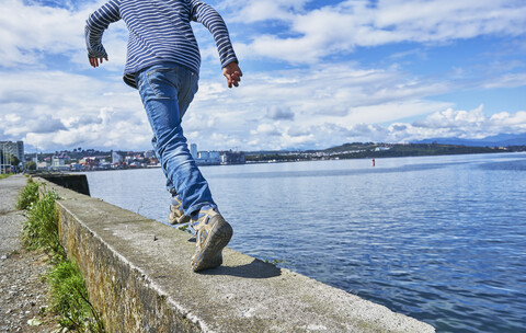 Chile, Puerto Montt, Junge läuft auf Kaimauer am Hafen, lizenzfreies Stockfoto