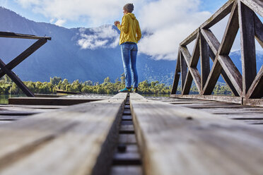 Chile, Chaiten, Lago Rosselot, woman standing on jetty holding mug - SSCF00217