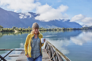 Chile, Chaiten, Lago Rosselot, woman walking on jetty holding mug - SSCF00218