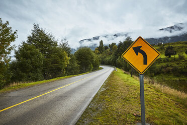 Chile, Puerto Aysen, Landstraße im Herbst mit kurvigem Straßenschild - SSCF00225