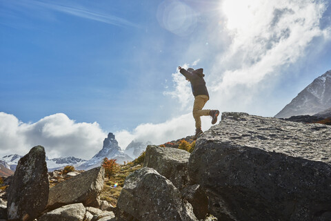 Chile, Cerro Castillo, boy jumping from rock in mountainscape stock photo
