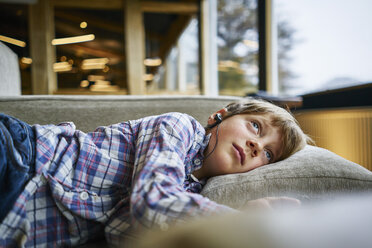 Junge auf Couch liegend mit Kopfhörern - SSCF00257