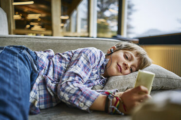 Junge auf der Couch liegend mit Kopfhörern und mp3-Player - SSCF00258