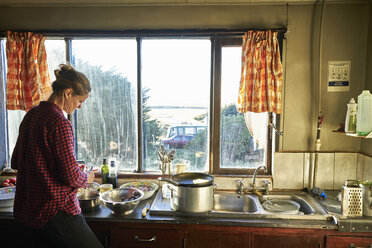Frau steht in der Küche und bereitet eine Mahlzeit vor - SSCF00263